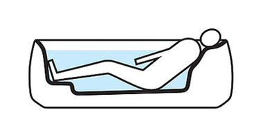 A person is lying in a bathtub equipped with recline Comfort technology. The small elevation in the floor is used as a footrest in this photo.