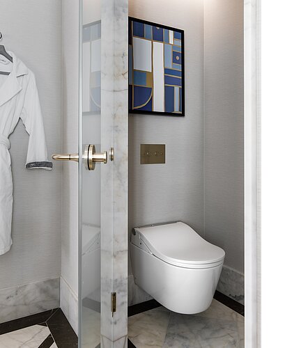 The photo shows a modern, wall-hung toilet in a stylish bathroom with marble tiles and a glass shower door on the left. Above the toilet hangs an abstract painting in blue and gold tones, which goes well with the elegant, gold-colored pressure plate and fittings.