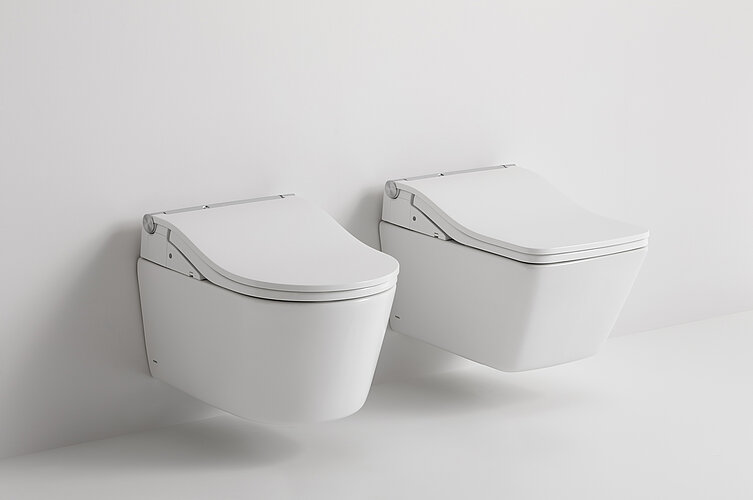 Das Foto zeigt zwei identische, moderne, wandhängende Toiletten nebeneinander vor einem weißen Hintergrund. Die schlichte Gestaltung betont die klaren Linien und die schlanke Silhouette der Sanitärkeramik.