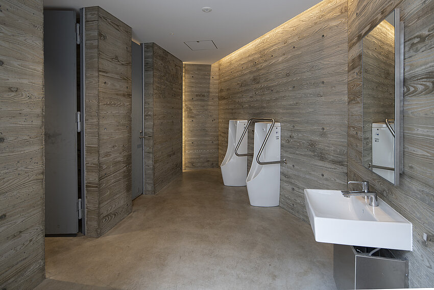 Vue intérieure des toilettes pour hommes du parc Ebisu. Les murs sont en bois.