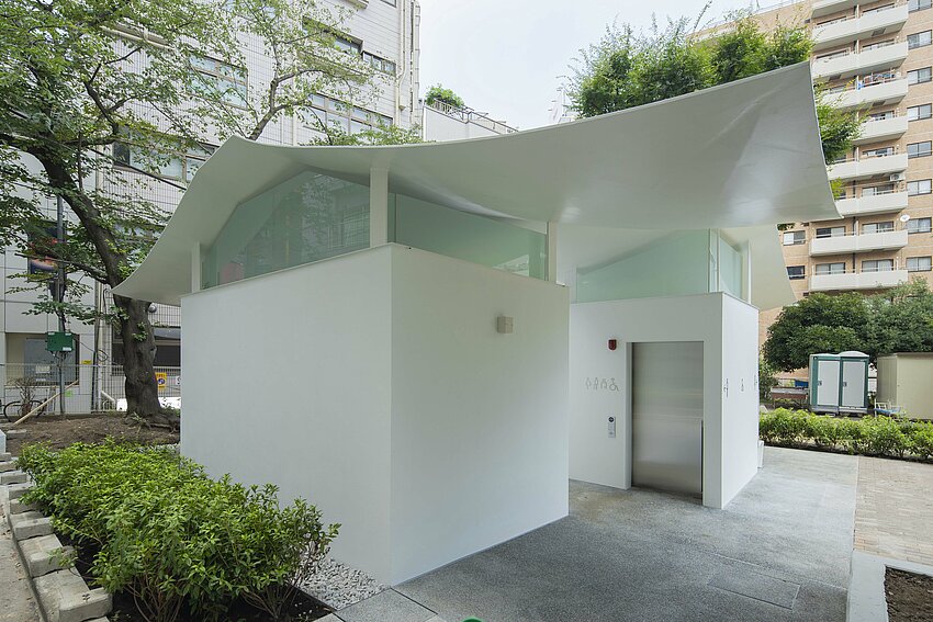 Une maison de toilette blanche avec un toit incurvé.
