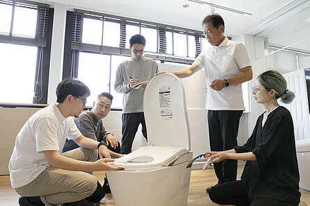 Several people are discussing a WASHLET standing in the middle of their circle.