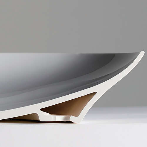 The picture shows a washbasin fitted with Lineceram. The washbasin is divided in the middle so that you can see the inside. The lower part, with which the washbasin stands on the floor, is a cavity. This cavity is located under the washbasin as a base. The hollow space closes at the top so that the upper part consists of a single ceramic. 