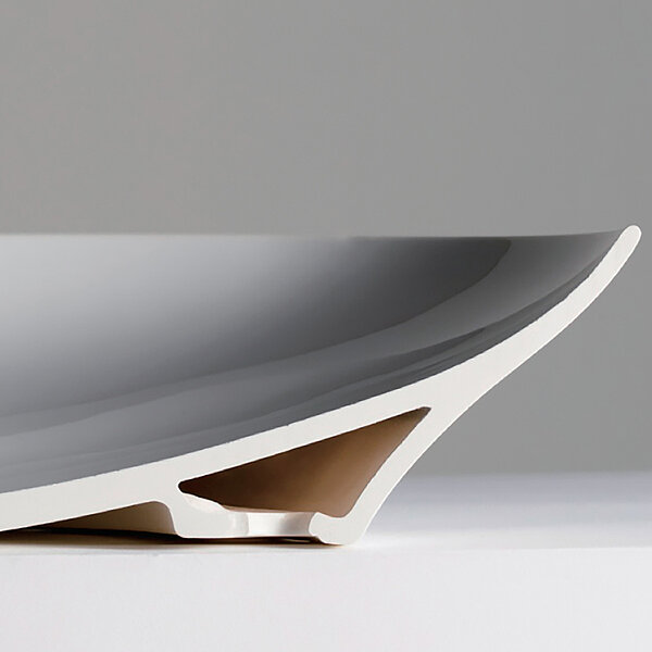 The picture shows a washbasin fitted with Lineceram. The washbasin is divided in the middle so that you can see the inside. The lower part, with which the washbasin stands on the floor, is a cavity. This cavity is located under the washbasin as a base. The hollow space closes at the top so that the upper part consists of a single ceramic. 