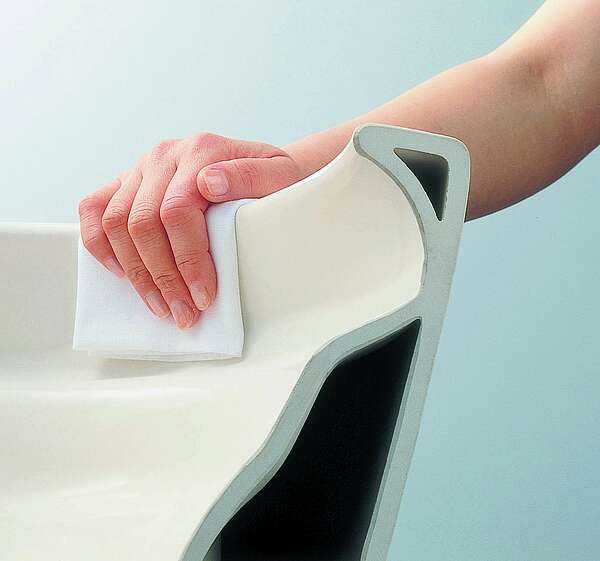 The illustration shows a rimless WC ceramic appliance being cleaned. The hand can wrap around the rim of the toilet with the cloth and clean it.