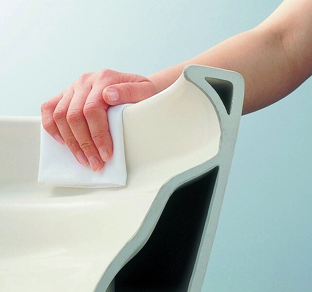 The illustration shows a rimless WC ceramic appliance being cleaned. The hand can wrap around the rim of the toilet with the cloth and clean it.