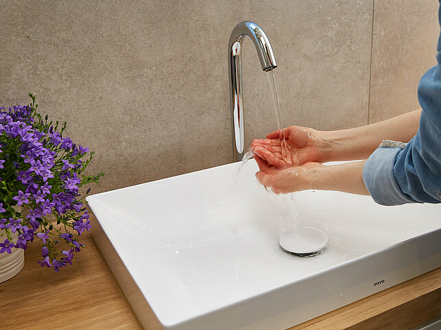 Eine Person wäscht sich die Hände in einem Waschbecken.