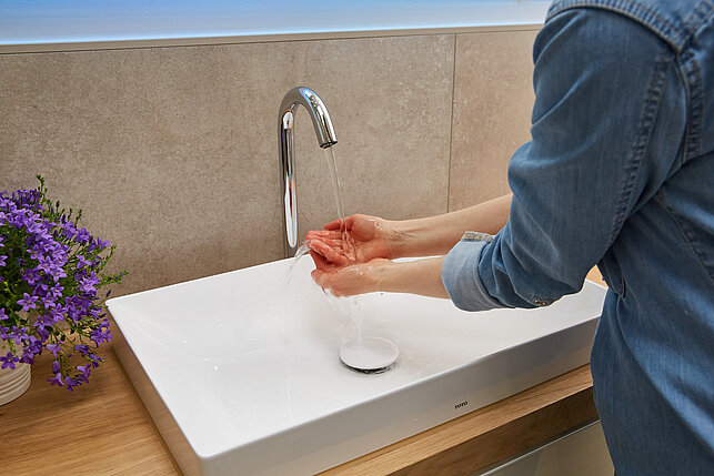 Une personne se lavant les mains dans un évier.