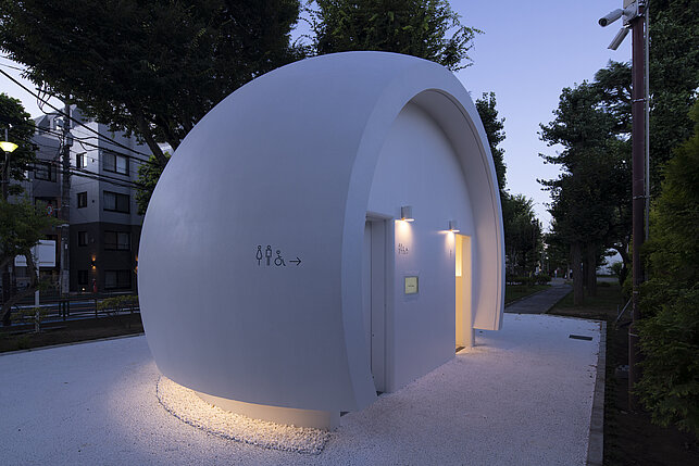 Une maison de toilette blanche en forme de demi-sphère.