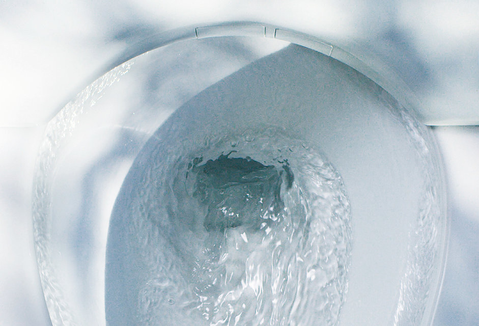 Vista della ceramica della toilette dall'alto. L'acqua scorre a spirale nello scarico.