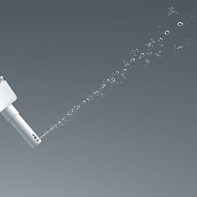 The picture shows a nozzle from which a slightly wider jet of water comes out, consisting of large drops.