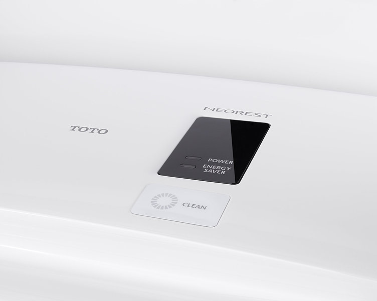 You can see a close-up of the display on the top of the Washlet. The words "Power" and "Energy Saver" appear in a black box next to two switched-off lights. Above this is the lettering "Neorest", to the left of this is the lettering TOTO and below this in a white box is the lettering "Clean" next to a gray circle.