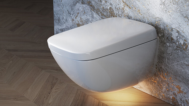 The image shows the elegant, wall-hung NEOREST WX from TOTO, which stands out with its sleek, white design, mounted on a wall with an eye-catching marble look. The toilet is illuminated by a warm, indirect light from below, which emphasizes the modern aesthetics of the product and creates a luxurious atmosphere.
