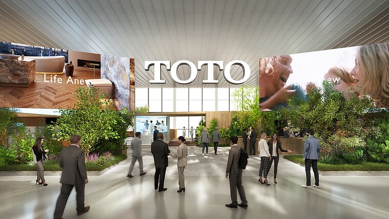 The image shows a computer-generated representation of TOTO's entrance area at the ISH trade fair, characterized by a large brand name on the wall and several screens displaying promotional content. The scene is animated with numerous visitors moving through an open hall surrounded by plants and well-lit, creating an inviting and interactive atmosphere.