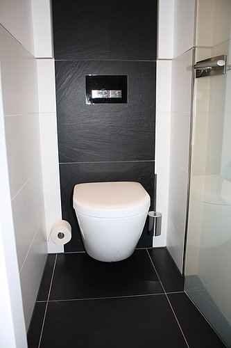 Wandhängende Toilette ohne Spülrand in roter WC Kabine