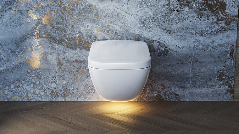 The picture shows a modern, wall-hung toilet in front of a wall with a striking marble look and a warm glow of light on the floor, giving the room a stylish and elegant atmosphere.