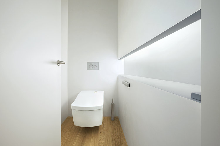 Wall-mounted WASHLET ™ Neorest AC in a white room with a wooden floor