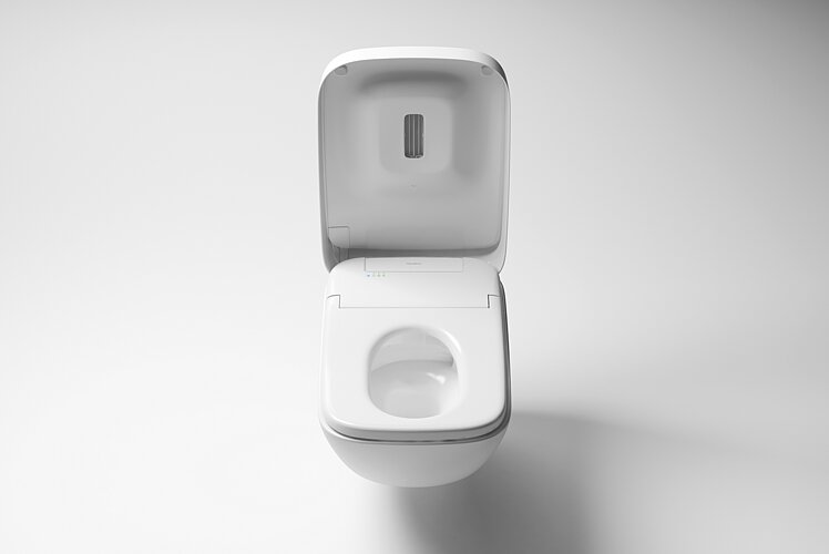 La photo montre une toilette moderne avec un couvercle ouvert, laissant clairement apparaître la technologie innovante à l'intérieur du couvercle. La toilette se trouve sur un fond uniformément clair, ce qui attire l'attention sur le design et la fonctionnalité du produit sanitaire.
