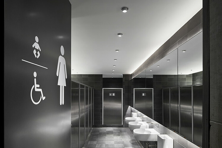 Anthracite-colored toilet area with white urinals and toilet cubicles