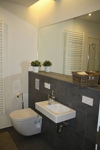 Toilettes suspendues avec lavabo devant un mur gris